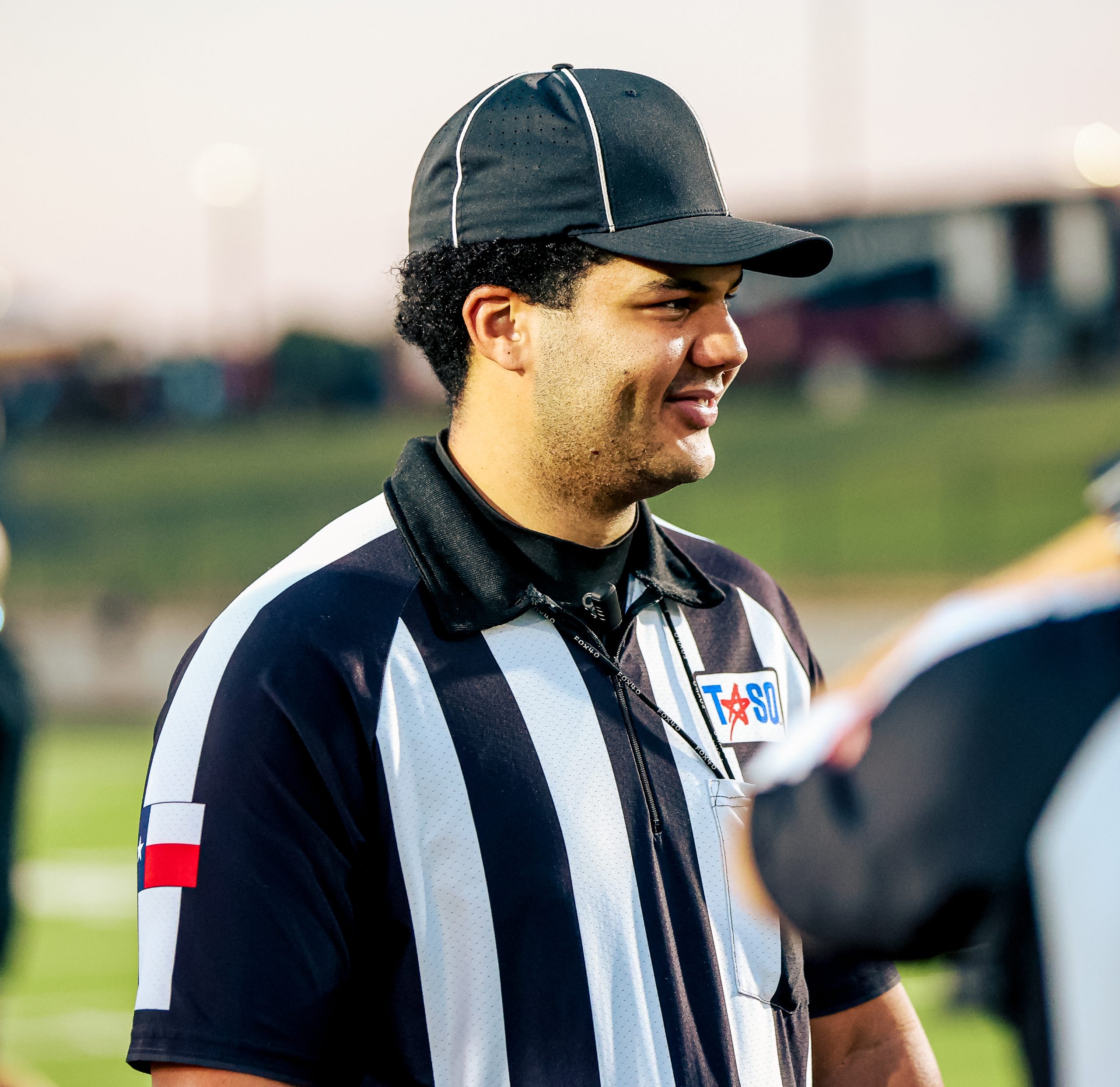 Football official in a black cap speaking at the sideline